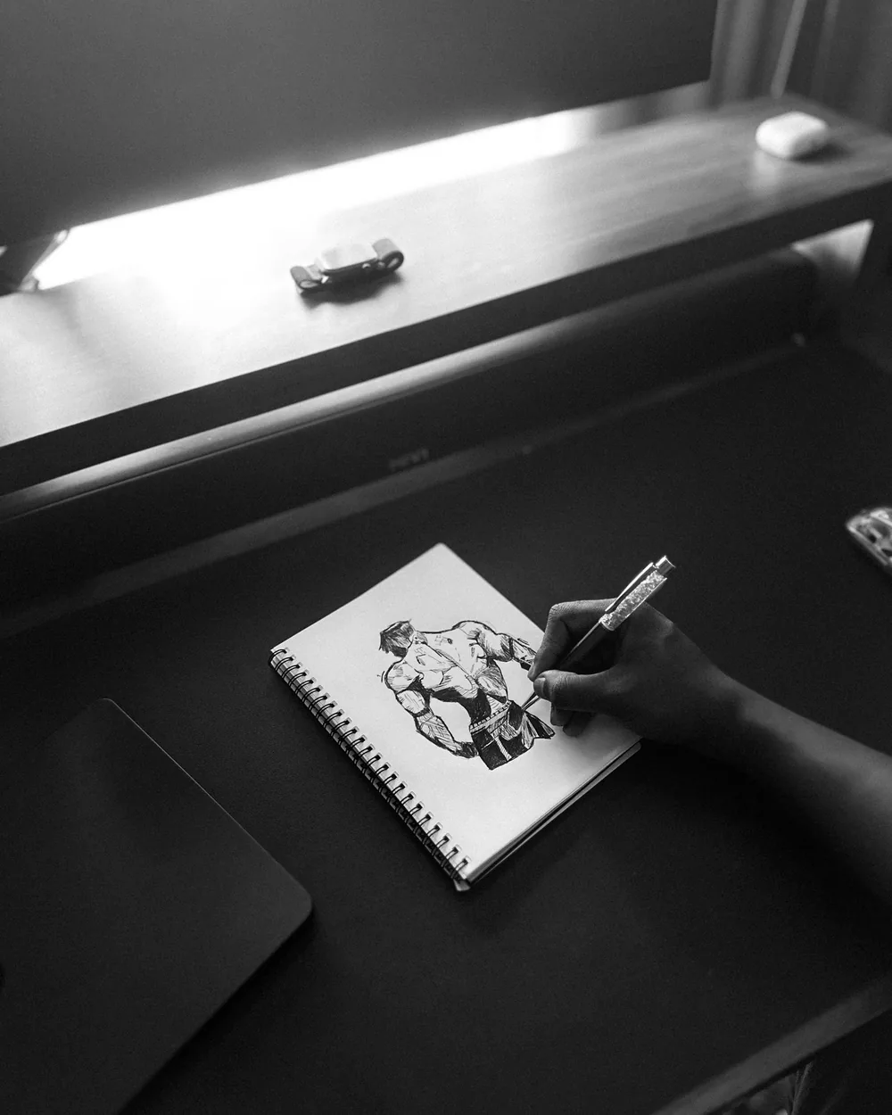Pracovní stůl s rozkreslenou komiksovou postavou v černobílé kresbě
